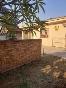 a brick retaining wall in front of a house at Plk Noord Guesthouse in Polokwane