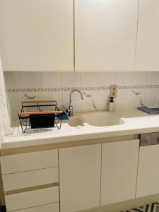 a white kitchen with a sink and a counter top at E.U. Woluwe Sweetheart Apartment in Brussels