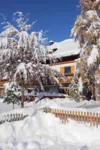 een huis bedekt met sneeuw met bomen en een hek bij Ferienwohnung Bergzauber Krün in Krün