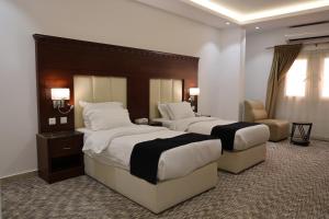 a hotel room with two beds and a chair at Al-faleh Hotel in Al Baha