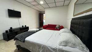 um quarto com uma cama grande e uma cadeira vermelha em Acogedor apartaestudio ubicado en la zona rosa de Pereira em Pereira