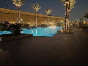 a large swimming pool with palm trees and lights at Carrara White 3BR APT W/Garden view and Pool in Cairo