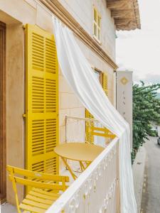 a table and chairs on a balcony with yellow shutters at Hotel Boutique Can Pocovi in Sant Llorenç des Cardassar