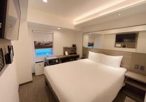 um quarto com uma grande cama branca e uma secretária em Smile Hotel Sapporo Susukino Minami em Sapporo