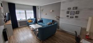 a living room with two blue chairs and a table at Friesenhaus1822 in Tettens in Wangerland