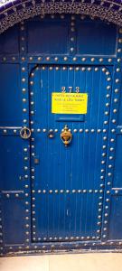 a blue door with a yellow sign on it at Riad Le Lieu in Tiznit
