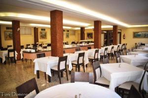 uma sala de jantar com mesas e cadeiras brancas em Hostal Sol de Mallorca em El Arenal