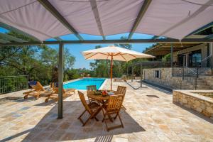 a patio with a table and umbrella next to a pool at Villa Gionis in (( Romanátika ))