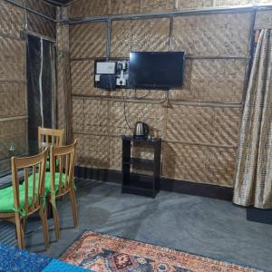 a room with a table and a tv on a wall at Alohi The terrace Homestay in Tezpur