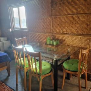 a dining room table with two chairs and a green seat at Alohi The terrace Homestay in Tezpur