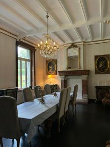 a dining room with a table and chairs and a chandelier at Château de Porcheresse in Daverdisse