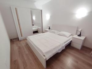 a white bedroom with a large white bed and a mirror at Central Residence in Baia Mare