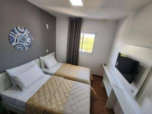 pokój hotelowy z 2 łóżkami i telewizorem w obiekcie Vincenzo Hotel w mieście São Vicente de Minas