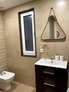 a bathroom with a sink and a toilet and a mirror at Piso en el centro de Ferrol recién reformado. in Ferrol