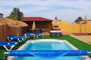 a pool with chairs and umbrellas next to a house at Luxury Villa at Golf Course in Costa de Antigua