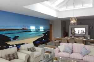 a living room with white furniture and a painting of a beach at Luxury Villa at Golf Course in Costa de Antigua