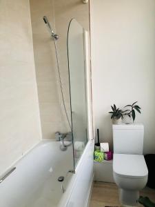 a bathroom with a tub and a toilet and a shower at 20 min to central London- 2 bedrooms apartment in London