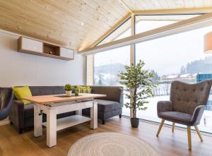 uma sala de estar com uma mesa e cadeiras e uma grande janela em Chalet Stuhleckblick- Ferienhaus mit eigener Sauna em Spital am Semmering