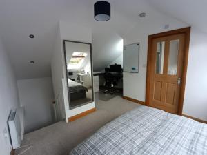 1 dormitorio con cama, espejo y escritorio en Entire modern cottage close to beach - Pet friendly en Gosport
