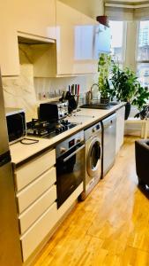 a kitchen with a stove and a washing machine at 20 min to central London- 2 bedrooms apartment in London