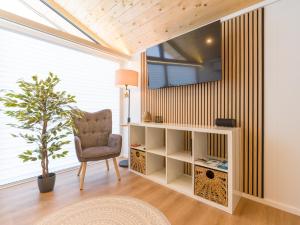 a living room with a chair and a tv on a wall at Chalet Stuhleckblick Ferienhaus mit Sauna, Panorama und Terrasse in Spital am Semmering
