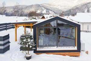 a house with a black roof in the snow at Chalet Stuhleckblick- Ferienhaus mit eigener Sauna in Spital am Semmering