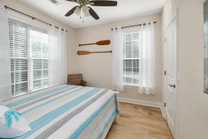 a bedroom with a bed and two windows at Palmetto Cottage in Saint Simons Island