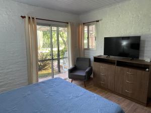 1 dormitorio con 1 cama, TV y silla en Magnolio, en Colonia del Sacramento