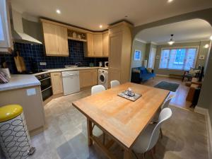 a kitchen with a wooden table and white chairs at Harbour Mews Central Location Near Beach in Whitstable +24 photos