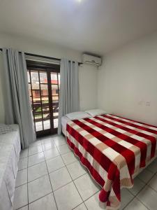 1 dormitorio con 1 cama con manta de rayas roja y blanca en Casa em Bombinhas Próximo a Praia, en Bombinhas