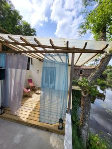une terrasse en bois avec une pergola à côté d'une masse d'eau dans l'établissement PETIT PARADIS, à La Bruffière