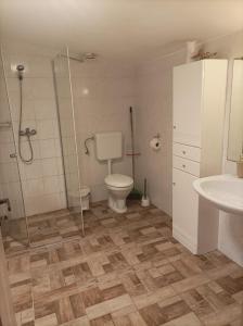 a bathroom with a toilet and a shower and a sink at Csilla Apartman in Balogunyom