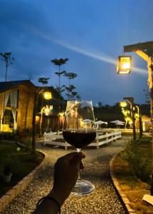a person holding up a glass of red wine at Mật Pet Farm - Mộc Châu in Mộc Châu