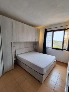 Residence Itaca Porto Pozzo في بورتو بوزو: غرفة نوم بسرير ونافذة