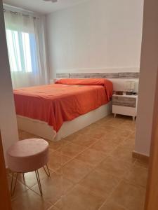 a bedroom with a bed with a red blanket and a stool at MOJACAR in Mojácar