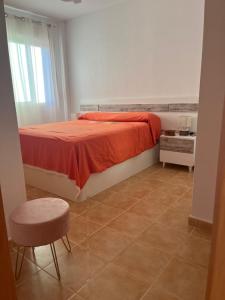 a bedroom with a bed with a red blanket and a stool at MOJACAR WITH POOL, BEACH AND GoLF in Mojácar