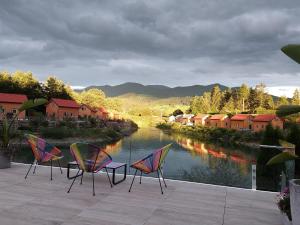 three chairs and a table on a patio next to a river at FERIENHAUS MOHN AM SEE in Spielberg