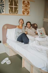 Ein Mann und eine Frau sitzen auf einem Bett mit Kuchen in der Unterkunft Hotel Jansen Amsterdam Bajeskwartier in Amsterdam