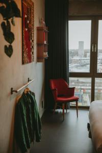 a hotel room with a red chair and a window at Hotel Jansen Amsterdam Bajeskwartier in Amsterdam