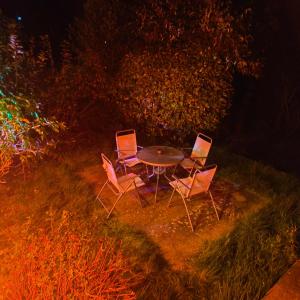 three chairs and a table in the grass at night at Private Entire House - 3 Bedrooms Garden Parking in Rottingdean