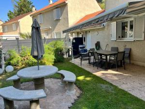 een patio met een tafel, 2 banken en een parasol bij Room in BB - Nathalies home - 2 Bedrooms Breakfast in Viry-Châtillon