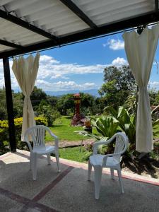 - deux chaises blanches sur une terrasse avec vue dans l'établissement casa campestre, à Fusagasuga
