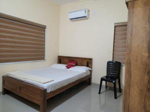 a bedroom with a bed and a black chair at Fathima Apartments in Iritti +6 photos