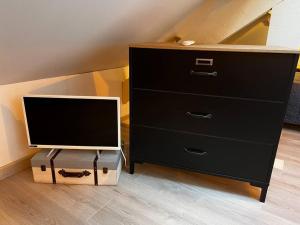 a dresser with a television on top of it at La Maison Sable - Chaleureuse Familiale avec Jardin-300m de la plage in Ouistreham