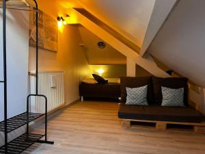 a room with a couch and a bed in a attic at La Maison Sable - Chaleureuse Familiale avec Jardin-300m de la plage in Ouistreham