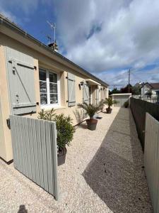 a house with a fence and plants in front of it at La Maison Sable - Chaleureuse Familiale avec Jardin-300m de la plage in Ouistreham