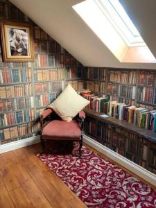 a library with a chair in a room with books at Rhedyn - Cosy Fishing Lodge Near Aberaeron in Cross Inn