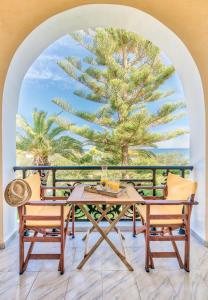 a table and chairs on a balcony with a palm tree at Panorama Studios & Apartments in Amoudi