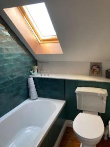 a bathroom with a tub and a toilet and a skylight at Rhedyn - Cosy Fishing Lodge Near Aberaeron in Cross Inn