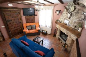 a living room with a blue couch and a fireplace at Casa Rural Los Arrieros in La Puerta